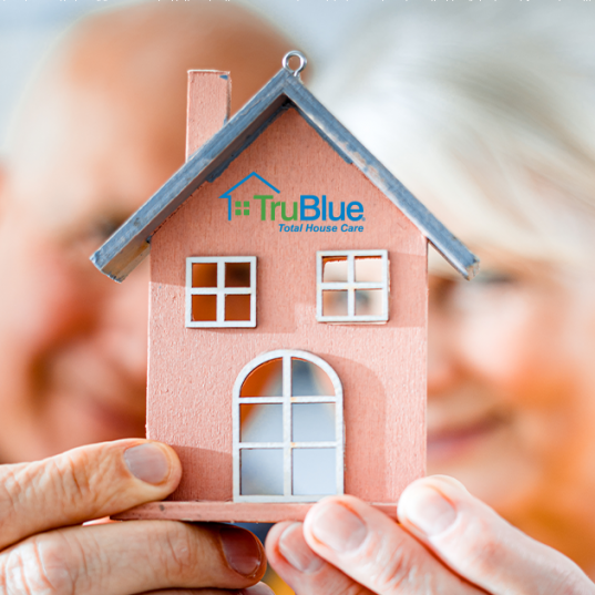 senior couple holding up toy home